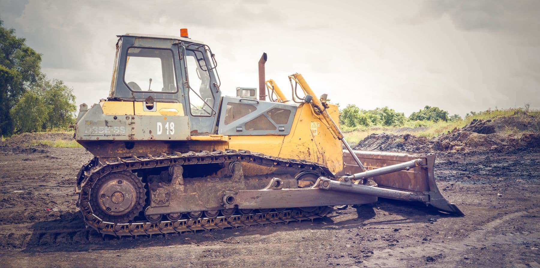 A bulldozer standing on a bare, cleared dirt lot.