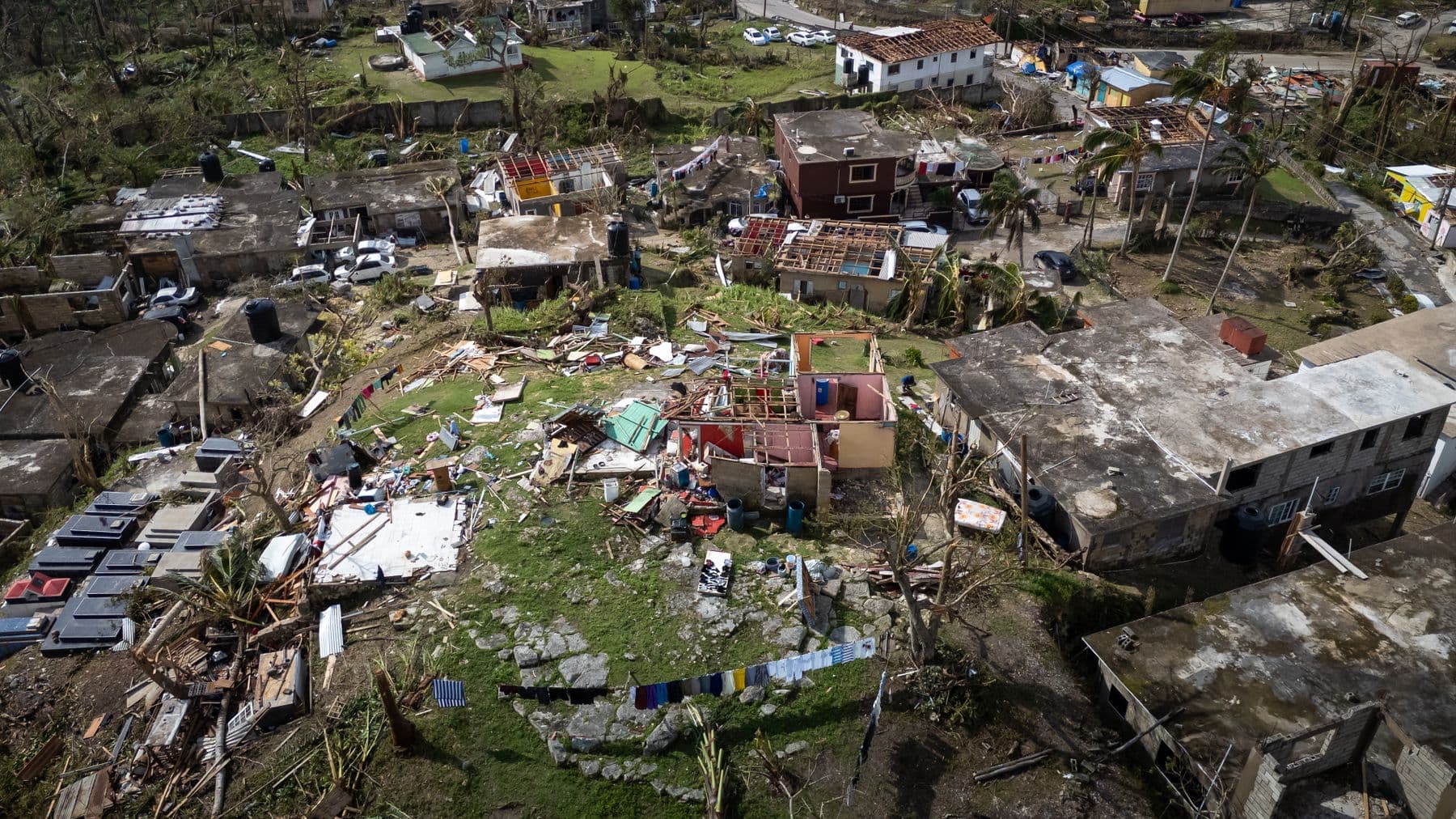 An aerial view of a neighborhood with roofs and buildings torn apart after a hurricane.