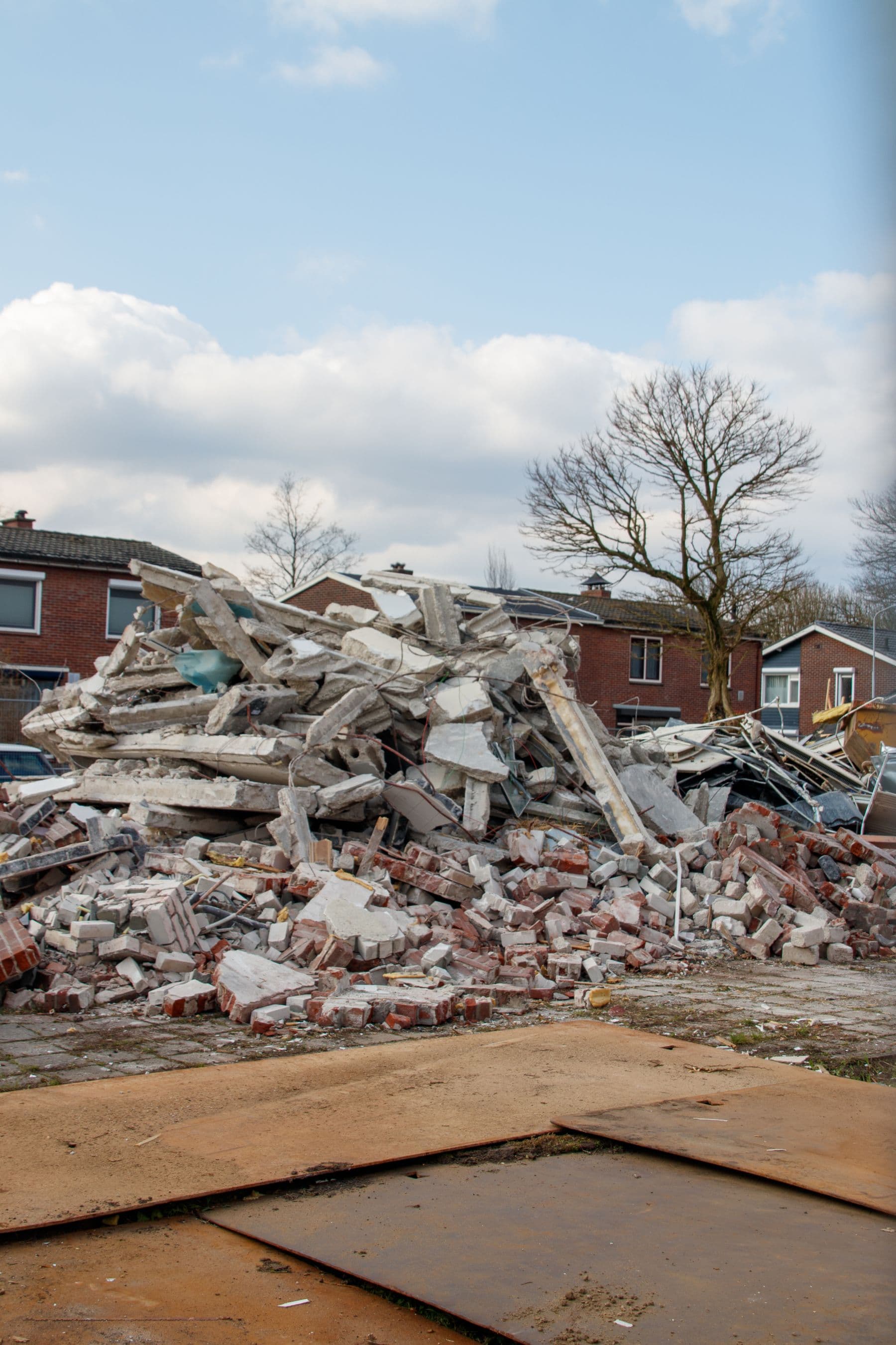 A pile of broken brick, concrete and wood left on a cleared demolition site.